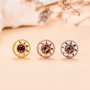 Dettaglio di tre orecchini a perno vintage in zircone color oro, argento e oro rosa