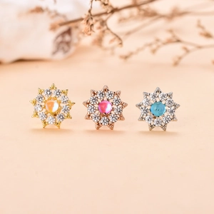 Vista dettagliata di tre orecchini a fiore vintage con zirconi in oro, oro rosa e argento