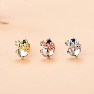 Dettaglio di piercing orecchio a stella con gemme blu in oro, oro rosa e argento