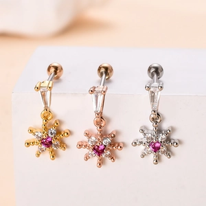 Macro detail of three snowflake navel rings in gold, rose gold, and silver finishes