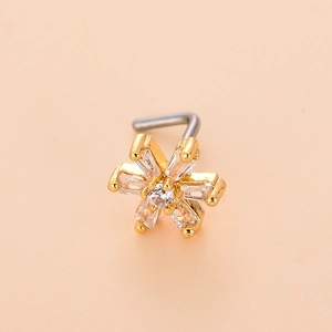 Macro detail of L-shaped gold flower nose stud with clear zircon stones on pink background