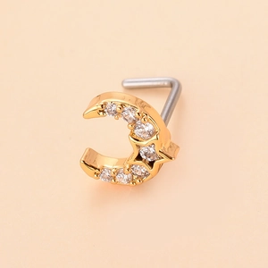 Macro view of gold L-shaped nose stud featuring star and moon motifs with zircon inlay