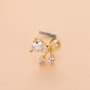 Close-up of golden L-shaped nose stud with crystal bow and heart-shaped zircon detail