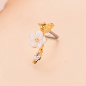 Detailed macro view of golden L-shaped nose stud with white flower and sparkling zircon stones