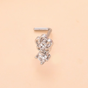 Detail view of L-shaped silver nose stud featuring dual zircons in a floral setting