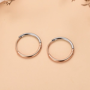 Detalle de pendientes de aro bicolor en oro rosa y plata con cierre de bisagra seguro