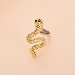 Macro shot of gold snake-shaped piercing jewelry with green and white zircons