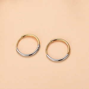 Primer plano de pendientes de aro bicolor oro y plata sobre fondo beige