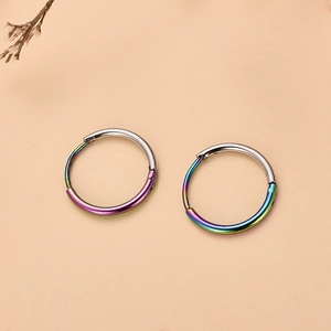 Detalle de pendientes de aro en acero inoxidable plata y arcoíris sobre fondo beige