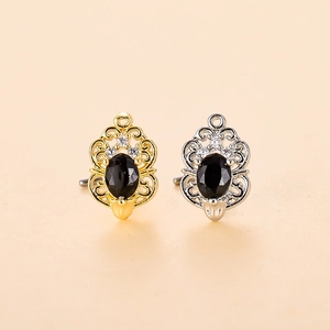 Dettaglio di orecchini vintage oro e argento con pietra nera ovale e piccoli zirconi