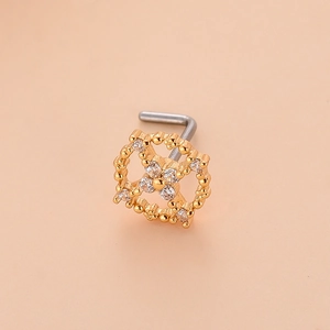 Macro d'un piercing nez en L doré avec motif fleur en croix et micro-pavage de zirconiums