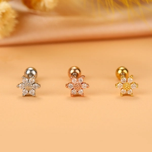 Dettaglio macro di orecchini per cartilagine a fiore in finiture argento, oro e oro rosa