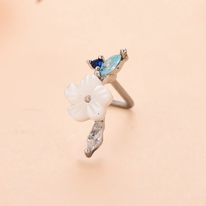 Macro shot of L-shaped nose stud with white flower and blue heart zircon detail