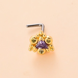 Macro detail of L-shaped nose stud with purple triangle zircon and green accent stones