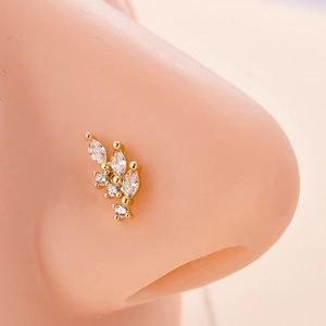 Dettaglio macro del piercing al naso dorato a forma di foglia con zirconi bianchi marquise