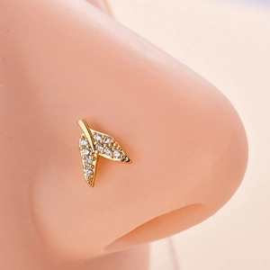 Dettaglio macro del piercing al naso a V dorato con zirconi incastonati su modello in silicone