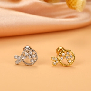 Close-up of gold and silver fish tail cartilage studs with micro-pave cubic zirconia