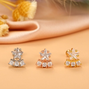 Star-shaped zircon ear studs in silver, gold, and rose gold finishes on silk background