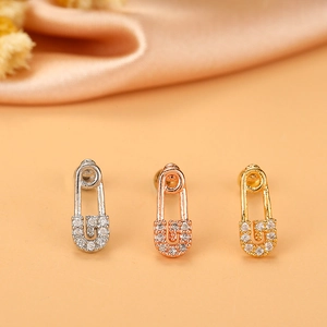 Close-up of three safety pin earrings in silver gold and rose gold with zircon stones