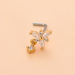 Détail du piercing de nez en forme de fleur dorée avec zircons et petit pendentif