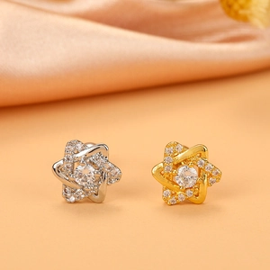 Detailed close-up of stacked star stud earrings with pavé crystals on champagne silk fabric