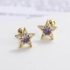 Macro shot of gold star-shaped stud earrings with purple stone and small zircon details