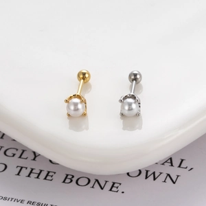 Detail of round white pearl screw back earrings in gold and silver finish