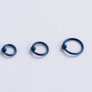 Confronto dettagliato di tre anelli con sfera prigioniera blu in diverse misure per piercing