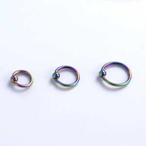 Dettaglio di anelli captive in acciaio medico 316L con finitura arcobaleno in varie misure