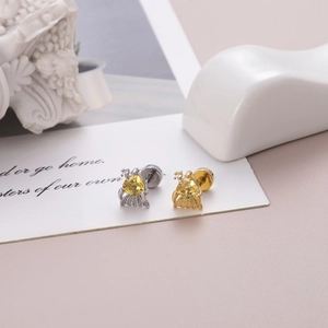 Dettaglio del piercing all'orecchio a fiore con zircone giallo e chiusura a sfera a vite