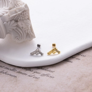 Dettaglio degli orecchini a forma di pistola in oro e argento con pietre di zircone