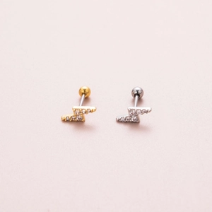 Detailed view of gold and silver lightning bolt piercings with zircon ball back closure