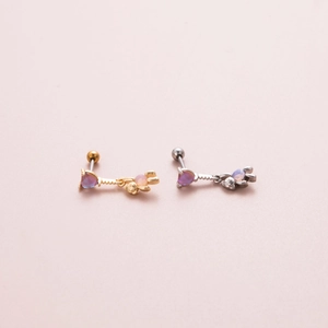 Close-up of gold and silver butterfly barbell earrings with purple and pink opal stones