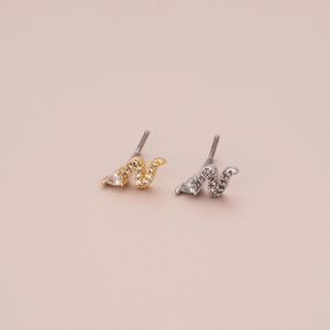Detail of L-shaped nose studs with shimmering curved pave crystals and teardrop gems