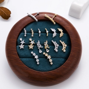 Vue macro de boucles d'oreilles ailes en acier 20G et clous en zircon sur plateau