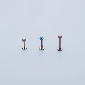 Detailed macro view of three rainbow-plated stainless steel labret studs in varying lengths