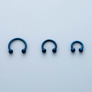 Three different sizes of blue horseshoe circular barbells for nose and ear piercings