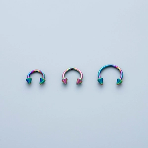 Macro detail of rainbow stainless steel horseshoe rings with spiked ends in three sizes