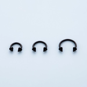 Three black 316 stainless steel horseshoe rings with spike ends in varying sizes