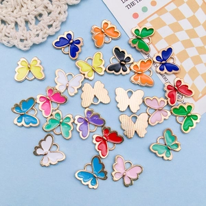 Detailed macro view of colorful enamel butterfly charms with gold metal frames for DIY