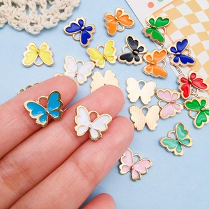 Hand holding colorful butterfly alloy oil drip charms for DIY jewelry making and crafts