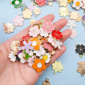 Bunte Emaille-Blumenanhänger aus Legierung in der Hand für DIY-Schmuckherstellung