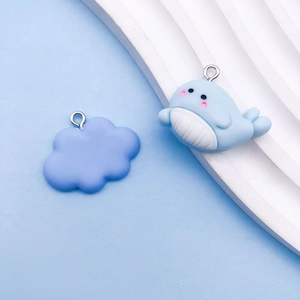 Detail of blue resin whale and purple cloud charms with metal rings for DIY jewelry