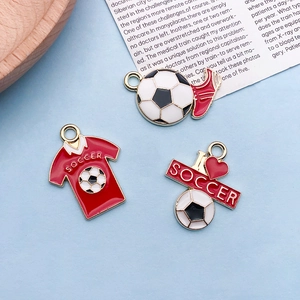 Detailed macro view of soccer themed enamel charms with gold finish and vibrant red oil drip