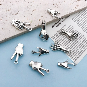Detail of antique silver hand gesture charms for DIY jewelry on a stylish background