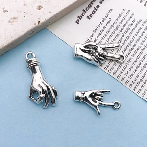 Close-up of three antique silver hand gesture charms for DIY jewelry making and crafts