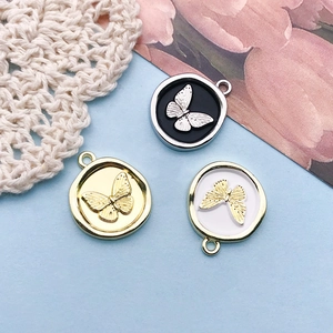 Detail view of round butterfly relief pendants in gold and silver for DIY jewelry