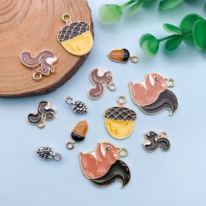 Cartoon enamel squirrel and acorn charms set on light blue background with greenery