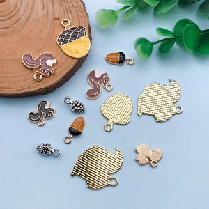 Enamel squirrel and acorn alloy charms set for DIY jewelry making on blue background