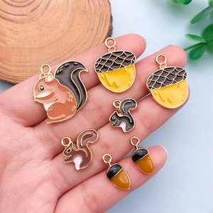 Detail of squirrel and acorn enamel charms for DIY jewelry held in hand